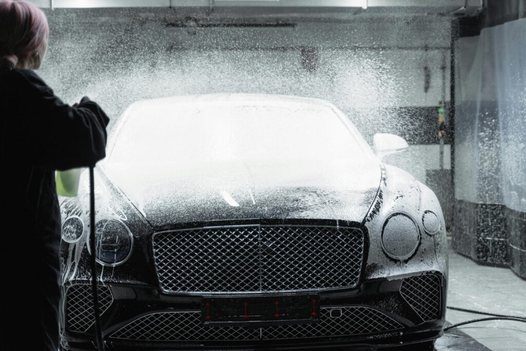 pexels-photo-6873191-6873191 Black luxury car receiving a foamy wash in an indoor car wash service.